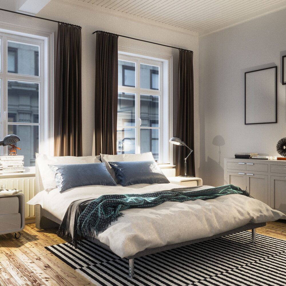 Bright bedroom with a double bed, large windows with dark curtains, bedside lamps and a sideboard; wooden floor and striped rug.